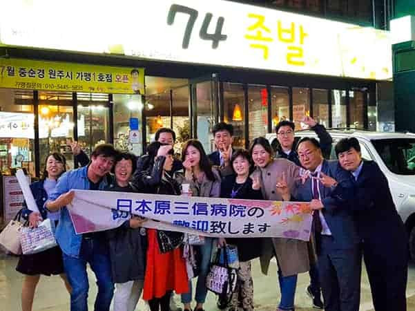 写真：お店の前で韓国東岡病院の研修グループが歓迎されている様子